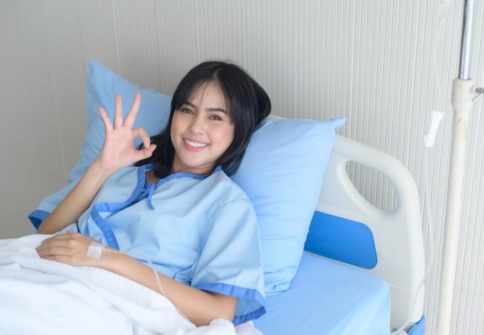 A smiling patient in a hospital bed.
